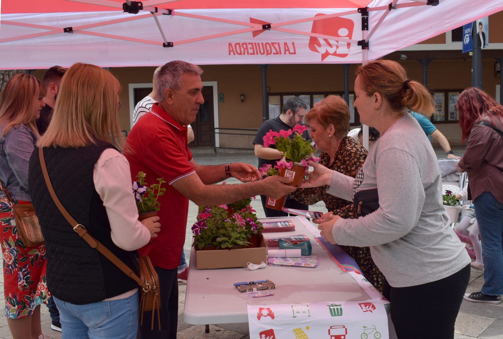 Los candidatos de IU regalando flores durante la mesa informativa